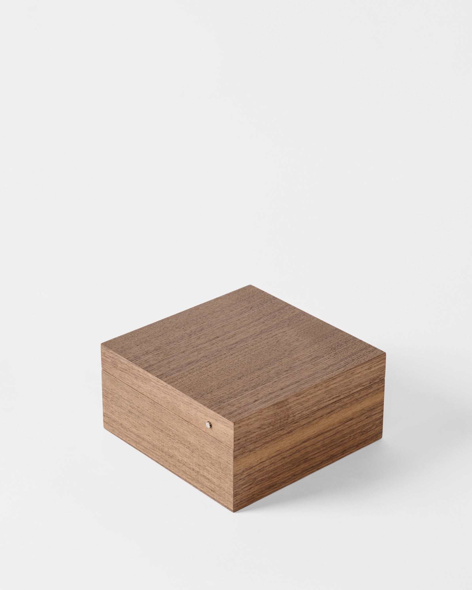 The TAWBURY Grove 6 Slot Wooden Watch Box features a small, square design in light walnut wood with a solid lid and smooth finish, complete with a metal hinge. Shown against a plain white background.