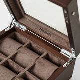The TAWBURY Grove 6 Slot Wooden Watch Box features a dark walnut wood finish, glass lid, metal hinges, and six brown fabric-lined compartments—ideal for elegant watch storage. "TAWBURY" is printed inside.