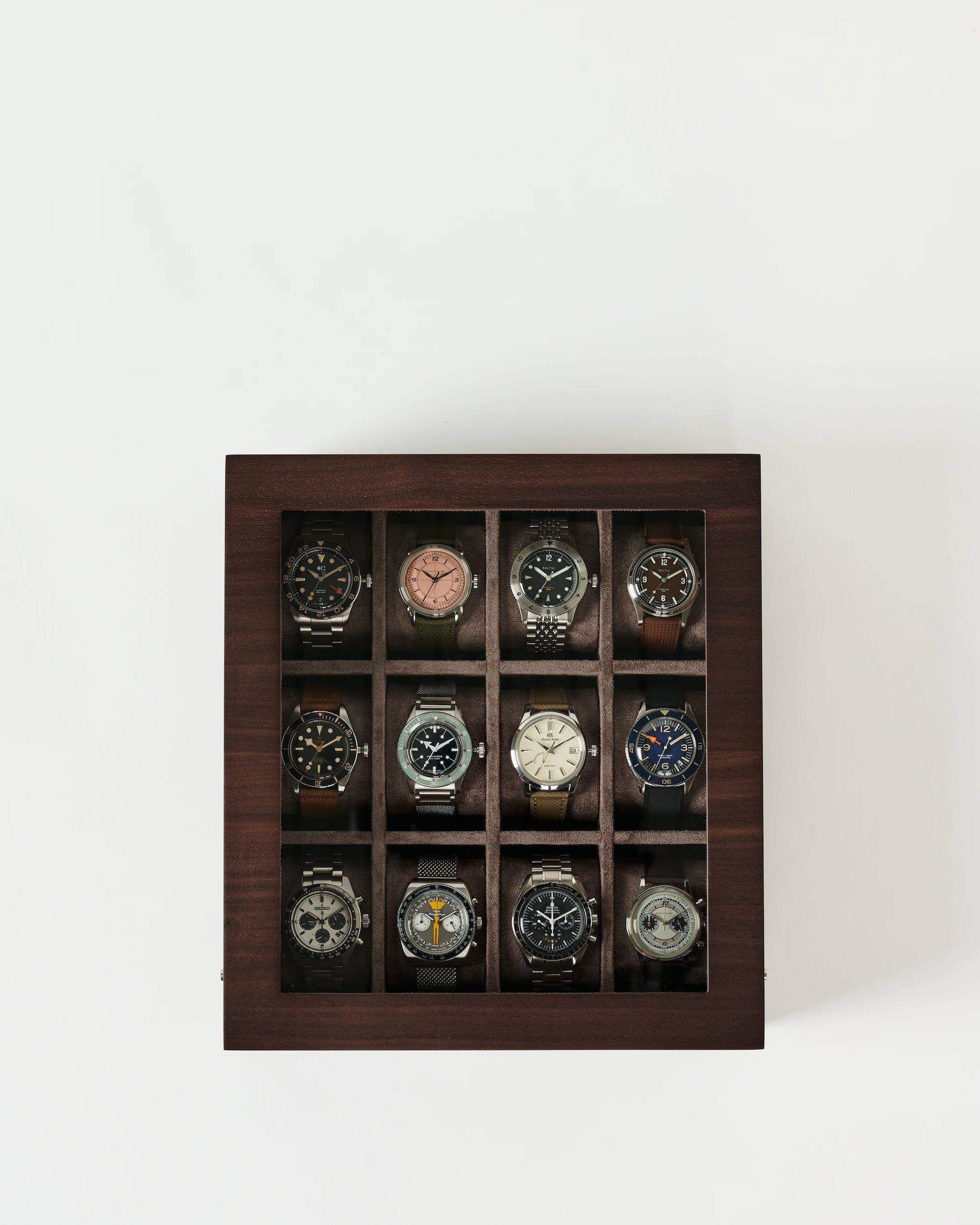 The TAWBURY Grove 12 Slot Wooden Watch Box in dark walnut wood features a glass lid and displays twelve wristwatches in three rows of four—ideal for collectors.