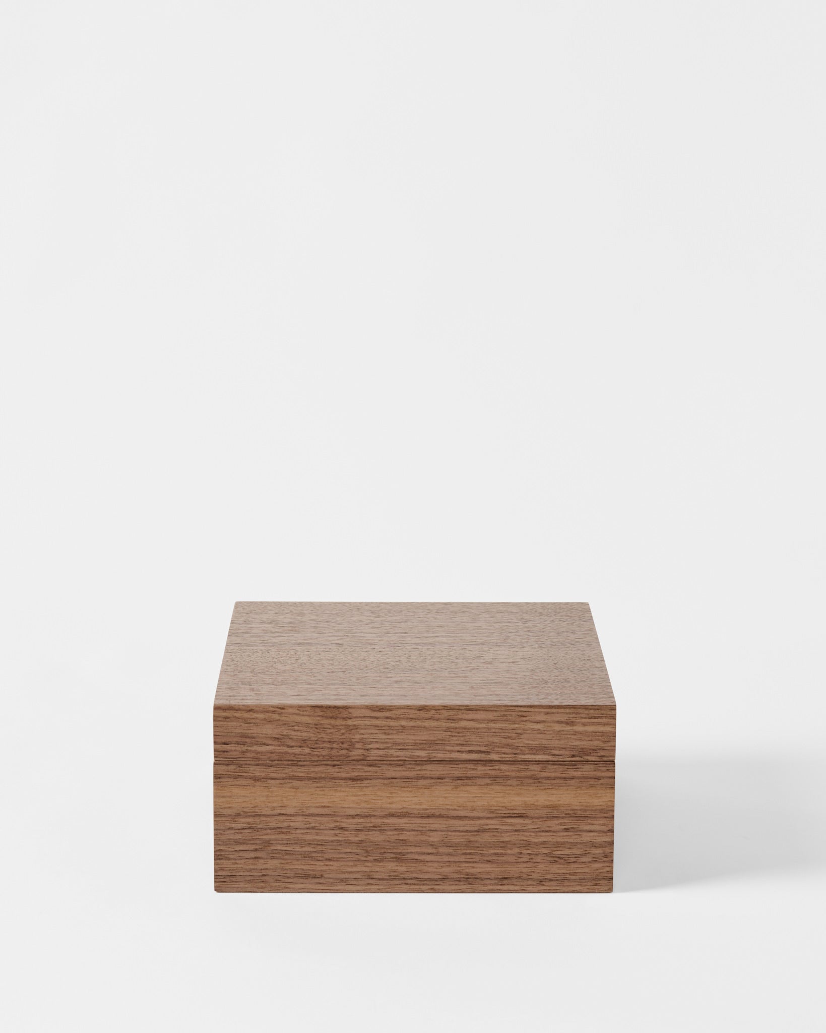A TAWBURY Grove 6 Slot Wooden Watch Box in Light Walnut with a solid lid sits closed on a white background.