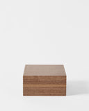 A TAWBURY Grove 6 Slot Wooden Watch Box in Light Walnut with a solid lid sits closed on a white background.