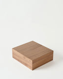 A TAWBURY Grove 12 Slot Wooden Watch Box in Light Walnut with a solid lid is displayed closed on a plain white background.