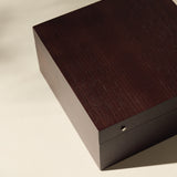 The TAWBURY Grove 6 Slot Wooden Watch Box, crafted from dark walnut wood with a solid lid, rests on a light surface and is photographed from above.