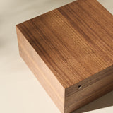 The TAWBURY Grove 6 Slot Wooden Watch Box in light walnut wood with a solid lid sits on a light surface, ideal for displaying and storing watches in style.