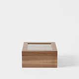 The TAWBURY Grove 6 Slot Wooden Watch Box in classic walnut features a transparent glass lid, shown on a plain white background—ideal for displaying your treasured timepieces.
