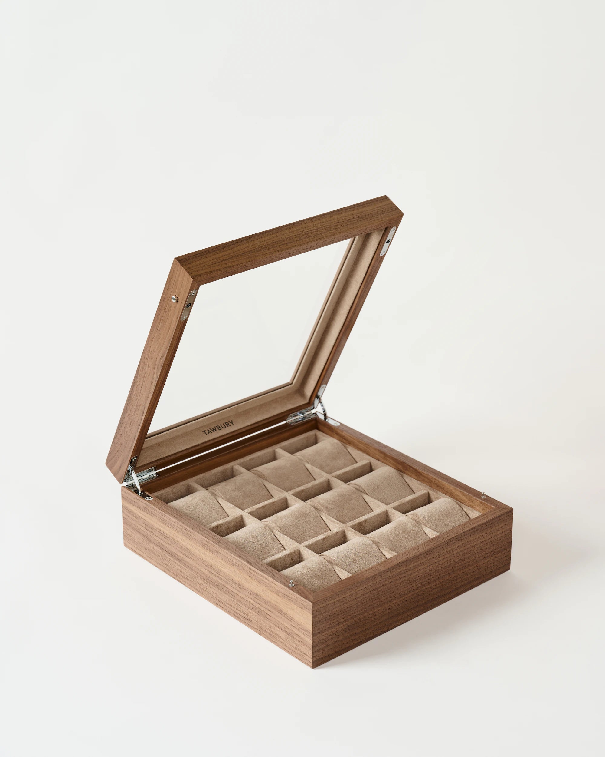The TAWBURY Grove 12 Slot Wooden Watch Box in light walnut features a glass lid and multiple beige velvet-lined compartments, perfect for organizing your watches or jewelry.