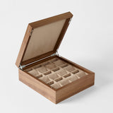 The TAWBURY Grove 12 Slot Wooden Watch Box in classic walnut features a closed hinged lid, beige fabric lining, and cushioned compartments for organized watch storage.