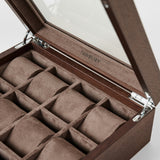 The TAWBURY Grove 12 Slot Wooden Watch Box in dark walnut features a glass lid, twelve suede-lined compartments, and an engraved logo inside—a stylish storage solution for watch collectors.