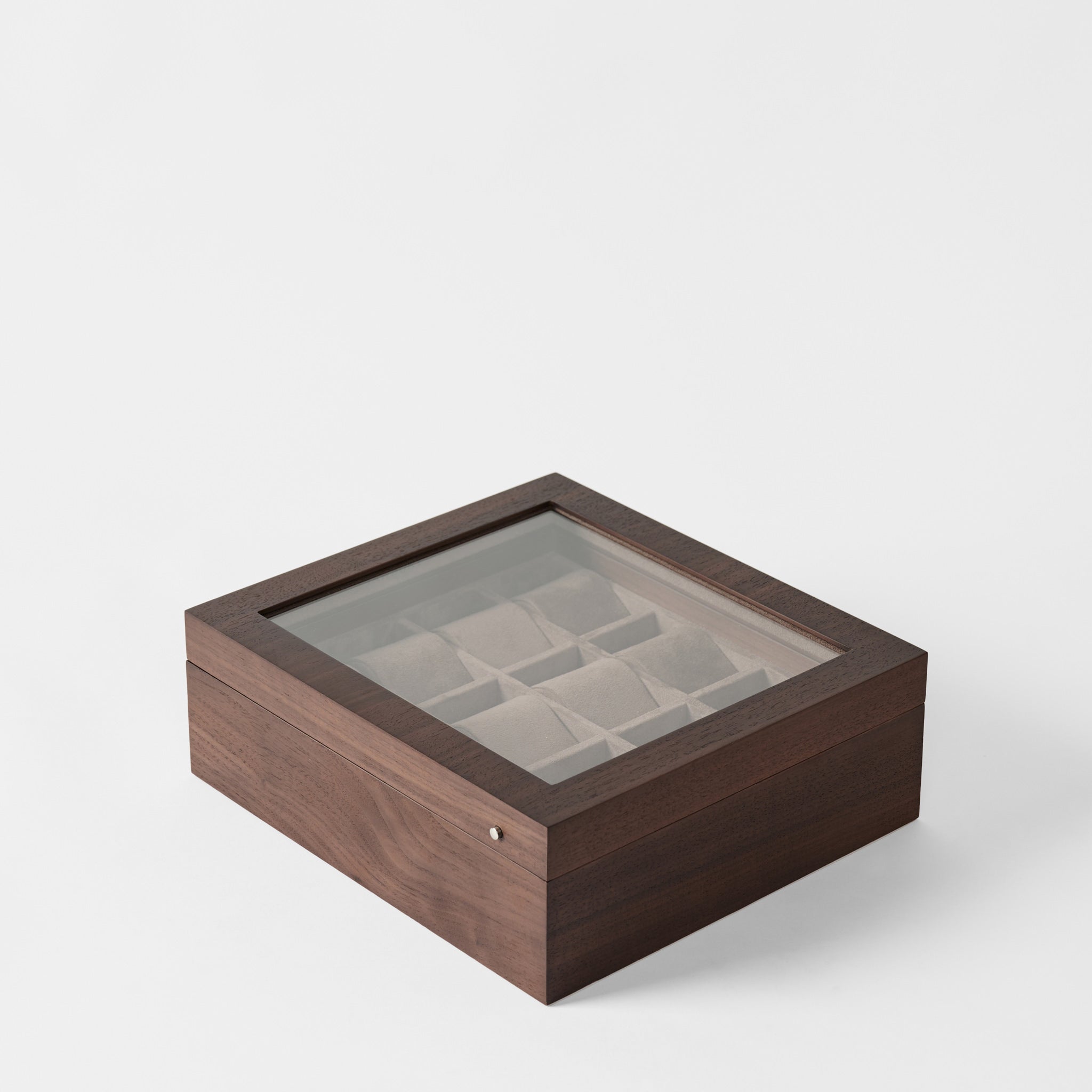The TAWBURY Grove 12 Slot Wooden Watch Box in Dark Walnut features a glass lid and multiple compartments for organizing watches or jewelry, shown against a plain white background.