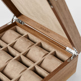 The TAWBURY Grove 12 Slot Wooden Watch Box, crafted from light walnut wood with a solid hinged lid and 12 padded compartments, is perfect for collectors; the TAWBURY logo is elegantly engraved inside the lid.