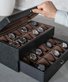 A man is using a TAWBURY Bayswater 24 Slot Watch Box with Drawer - Black to organize and protect his collection of watches.