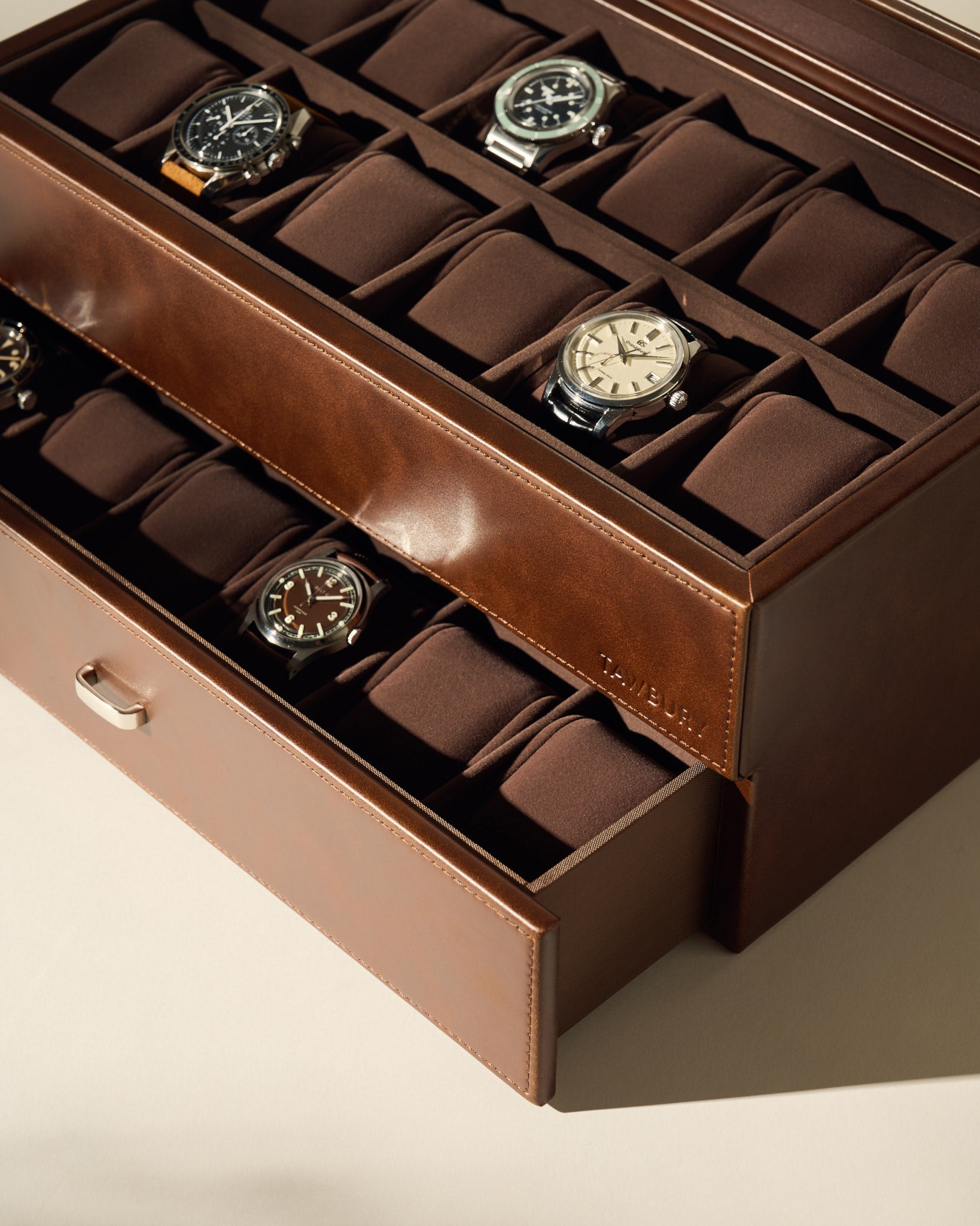 The TAWBURY Bayswater 24 Slot Watch Box with Drawer in brown neatly displays your watch collection on cushioned slots, offering stylish and practical storage.