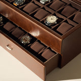 The TAWBURY Bayswater 24 Slot Watch Box with Drawer in brown neatly displays your watch collection on cushioned slots, offering stylish and practical storage.