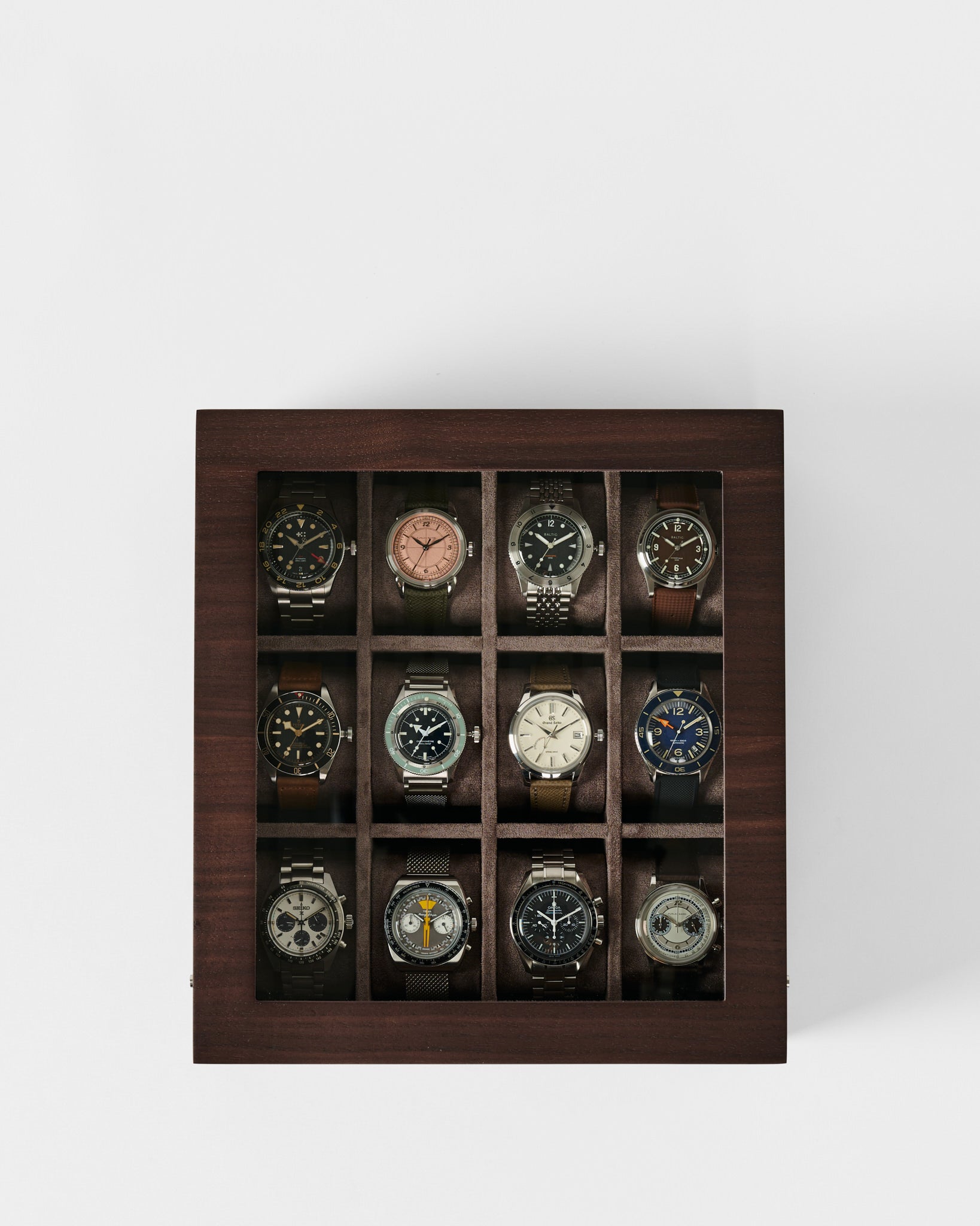 The TAWBURY Grove 12 Slot Wooden Watch Box in dark walnut wood features a glass lid and showcases twelve wristwatches, each in its own compartment—an elegant storage solution for collectors.