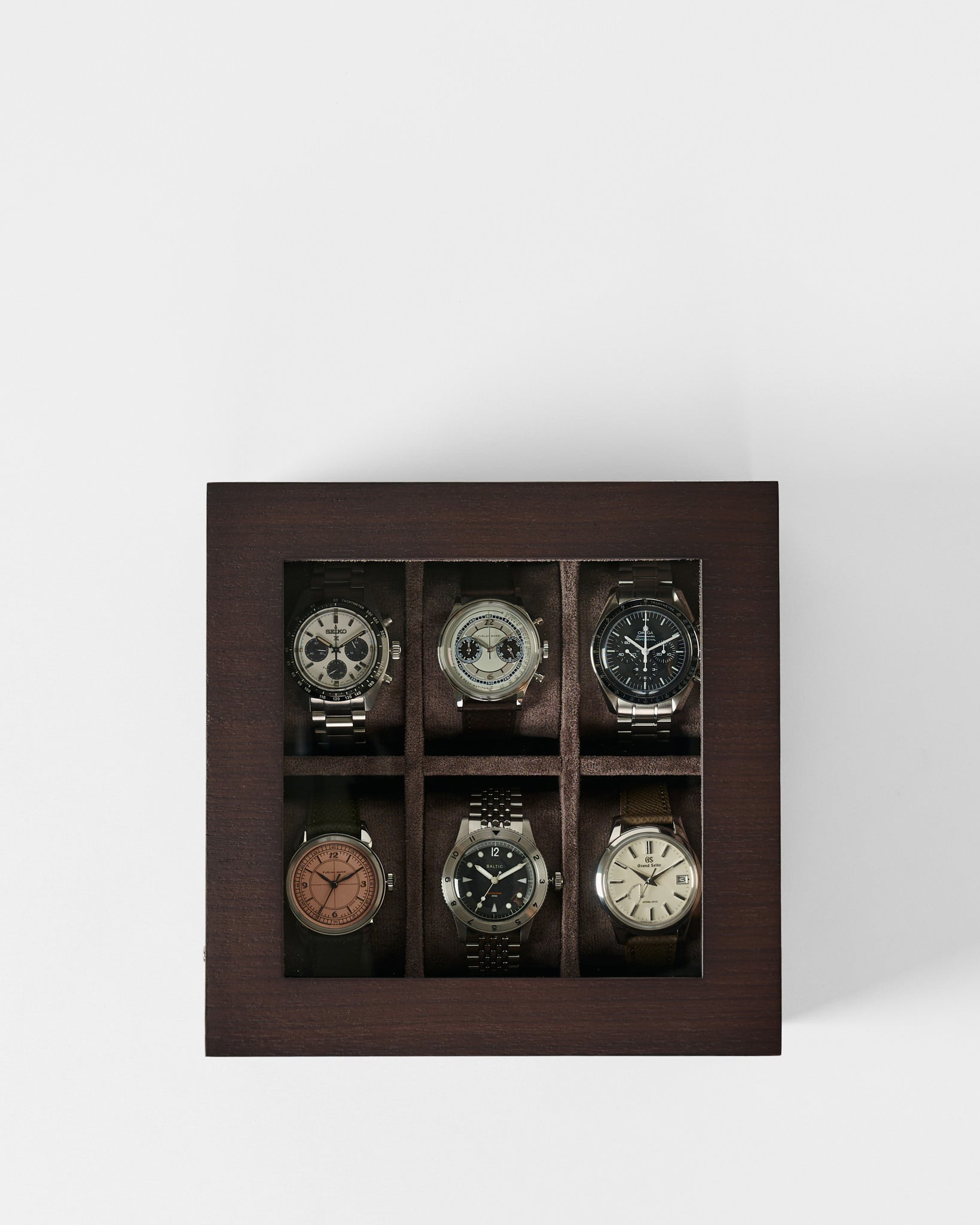 Showcase your watches in style with the TAWBURY Grove 6 Slot Wooden Watch Box. Crafted from dark walnut wood with a glass lid, it stores six wristwatches separately in two rows of three for elegant display and protection.
