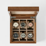 The TAWBURY Grove 6 Slot Wooden Watch Box in Light Walnut Wood with a solid lid elegantly displays six wristwatches, each in its own compartment—ideal as a refined storage case for your watch collection.